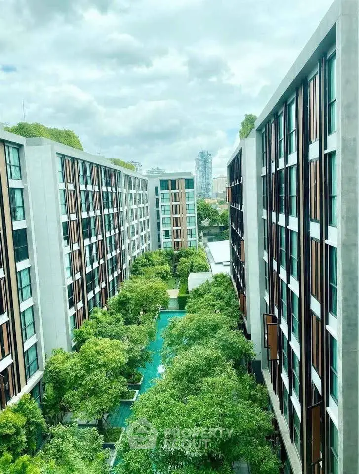 Modern apartment complex with lush green garden and city view