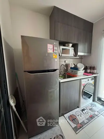 Compact kitchen with modern appliances including fridge and washing machine, ideal for urban living.