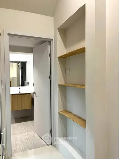 Modern bathroom entrance with sleek shelving and contemporary sink design.