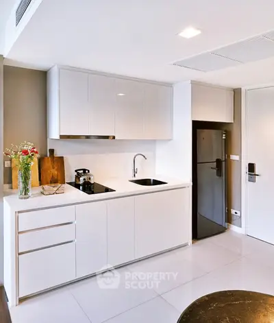 Modern kitchen with sleek white cabinets and stainless steel appliances in a stylish apartment.