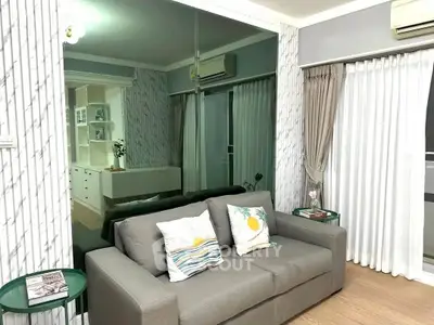 Modern living room with stylish decor and large mirror wall, featuring a cozy gray sofa and elegant curtains.