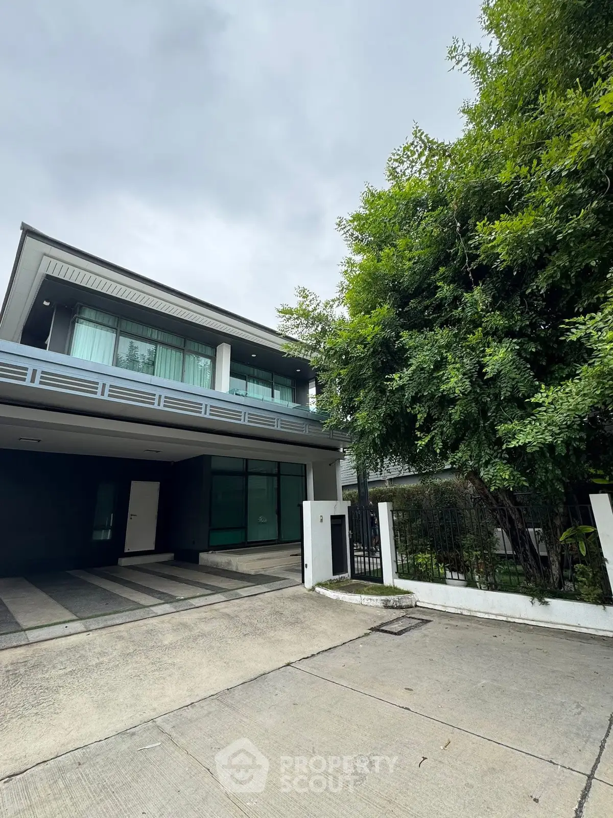 Modern two-story house with spacious driveway and lush greenery