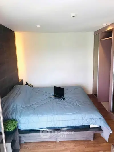 Cozy bedroom with modern decor and natural light, featuring a comfortable bed and wooden flooring.