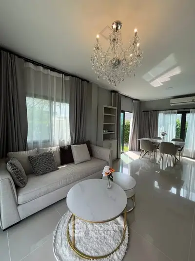 Elegant living room with chandelier, modern furniture, and large windows offering natural light.