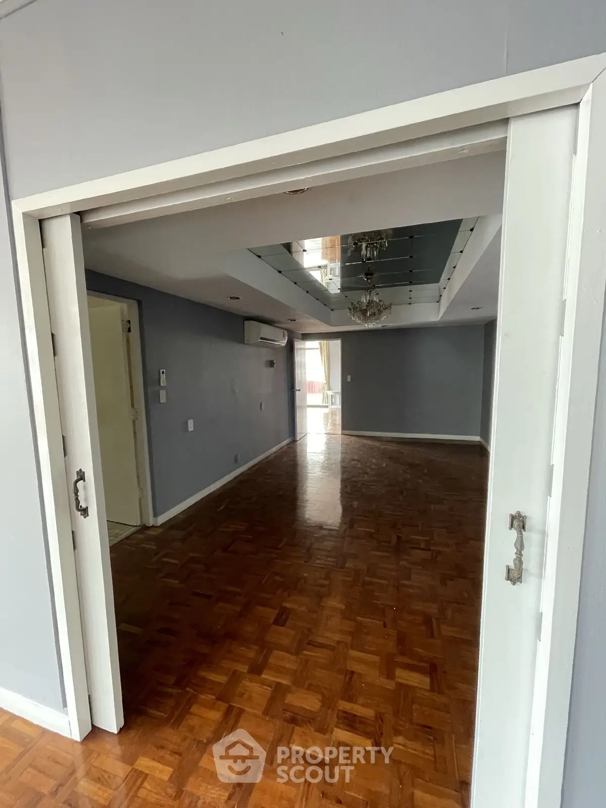 Spacious empty living room with wooden flooring and sliding doors, perfect for customization.