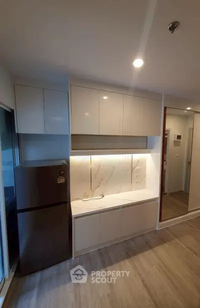 Modern kitchen with sleek cabinetry and stainless steel fridge in a stylish apartment.