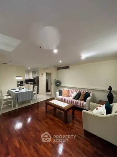 Spacious living room with cozy seating and dining area, featuring elegant wooden flooring.