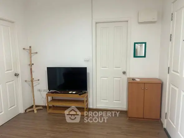Cozy living room with TV and wooden flooring, perfect for relaxation.