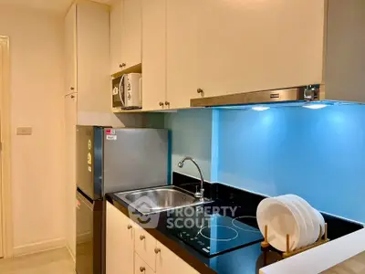 Modern kitchen with sleek black countertops, stainless steel appliances, and under-cabinet lighting.