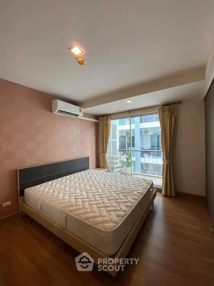 Spacious bedroom with large window and modern decor in urban apartment