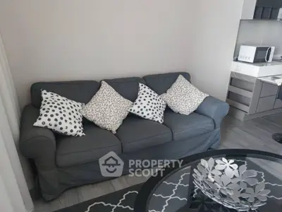 Chic modern living space with a stylish grey sofa adorned with patterned cushions, sleek furnishings, and a decorative centerpiece on the coffee table.