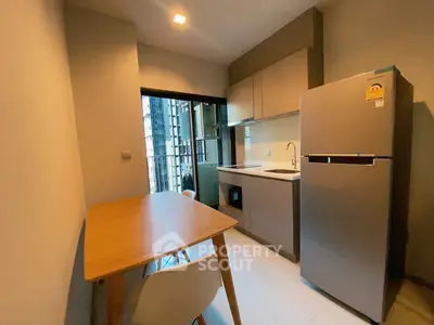 Modern kitchen with sleek cabinetry and stainless steel fridge in a cozy apartment setting.