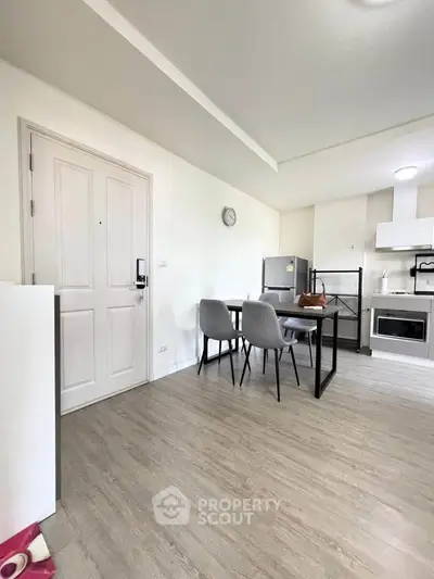 Modern apartment interior with dining area and kitchen featuring sleek appliances and minimalist design.