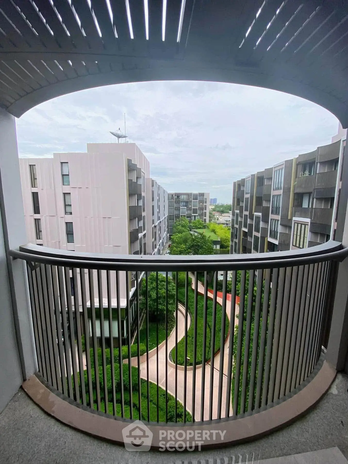 Stunning view from a modern balcony overlooking lush gardens and contemporary architecture.