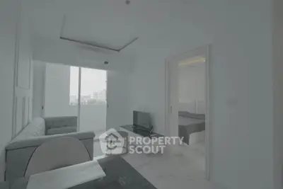 Modern minimalist living room with balcony and bedroom view in a bright apartment.