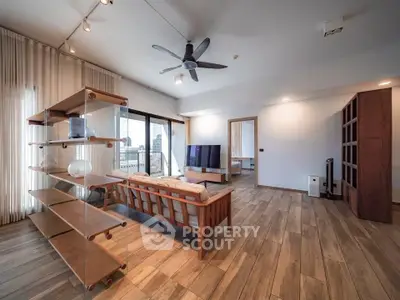 Spacious modern living room with wooden flooring and stylish furniture, featuring a large balcony with city view.