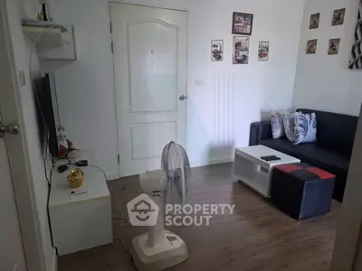 Cozy living room with modern decor and wooden flooring, featuring a comfortable sofa and entertainment setup.