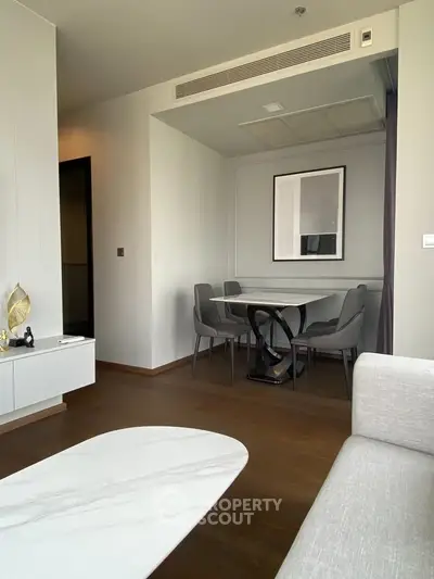 Modern living room with elegant dining area and stylish decor, featuring wooden flooring and contemporary furniture.