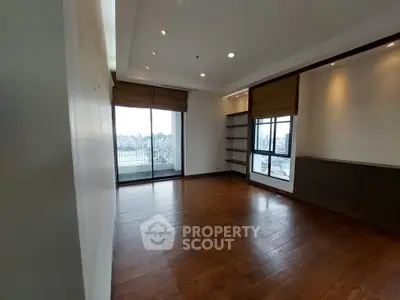 Spacious living room with wooden flooring and large windows offering city views.