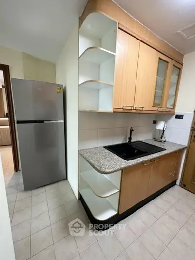Modern kitchen with sleek cabinetry and granite countertops in a cozy apartment setting.