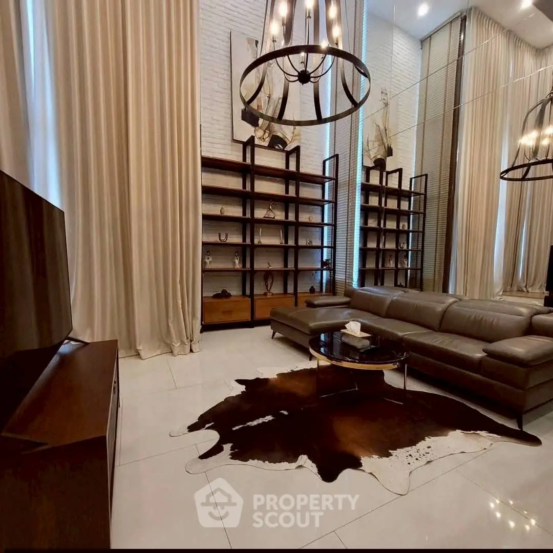 Luxurious living room with high ceilings, elegant chandeliers, and modern leather sofa.