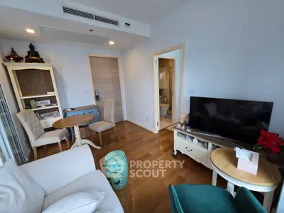 Charming living room with modern decor and wooden flooring, featuring a cozy seating area and a flat-screen TV.