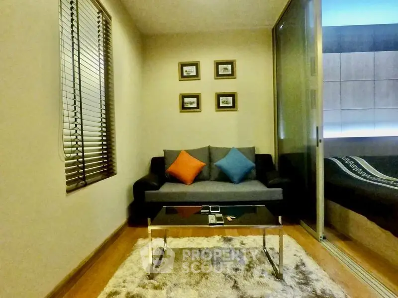 Cozy living room with modern sofa, colorful cushions, and stylish decor in a compact apartment.
