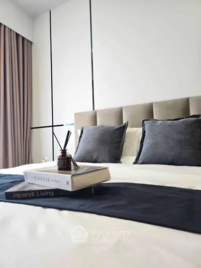 Modern bedroom with stylish decor and cozy ambiance, featuring elegant pillows and books on the bed.