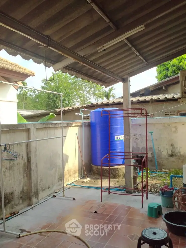 Outdoor utility area with water tank and laundry setup