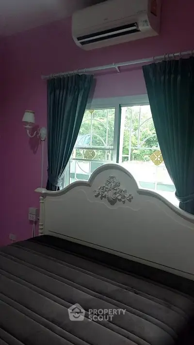 Charming bedroom with elegant bed frame and lush garden view through window.