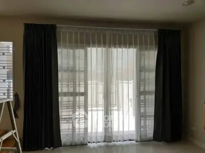 Spacious living room with large windows and elegant curtains, perfect for natural light and modern decor.