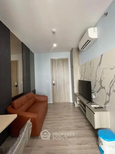 Modern living room with sleek design, featuring a brown sofa, wall-mounted TV, and air conditioning.