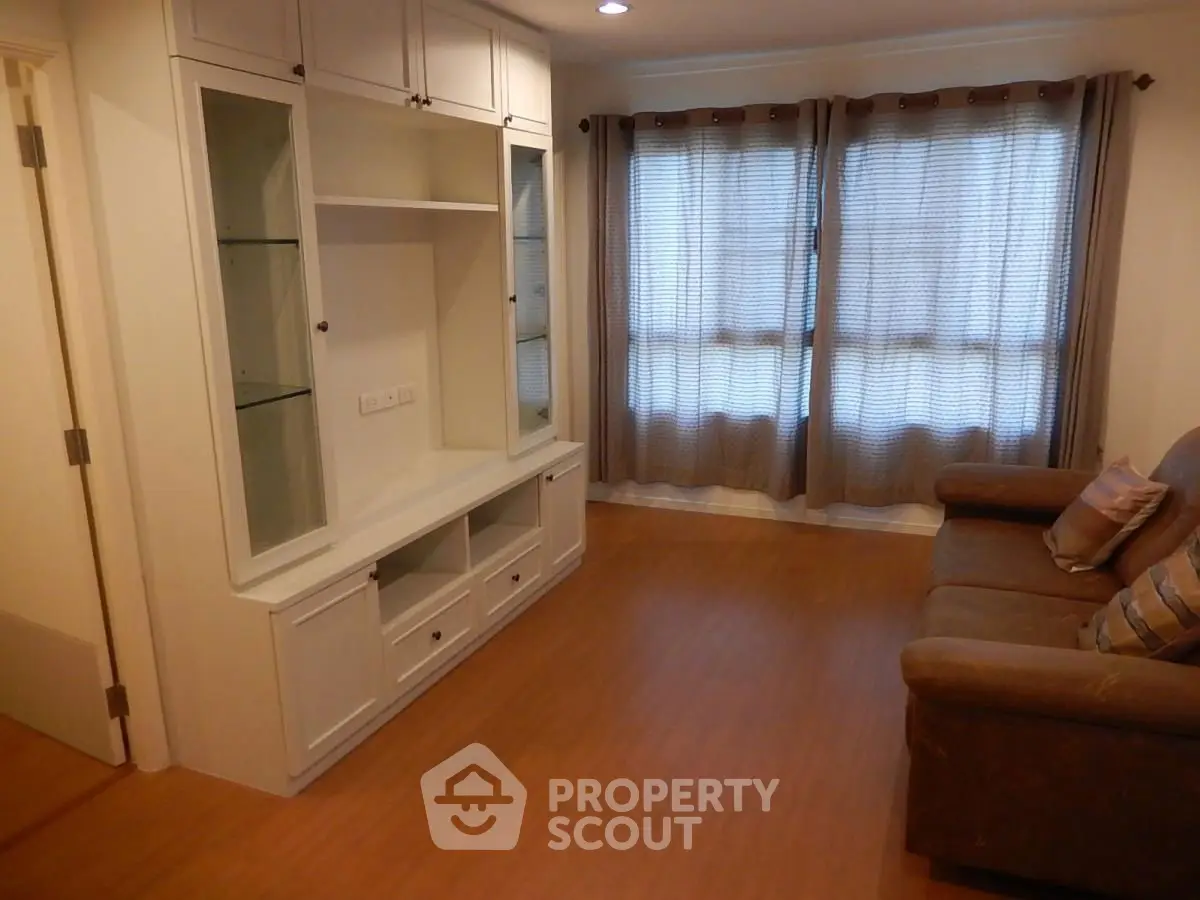 Cozy living room with built-in shelving and large window, perfect for relaxation.