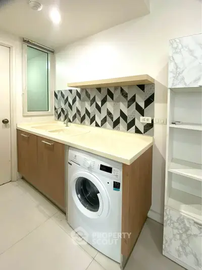 Modern kitchen with washing machine and stylish backsplash in a contemporary apartment.