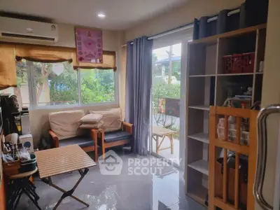 Cozy living room with large windows and garden view, featuring modern furniture and ample natural light.