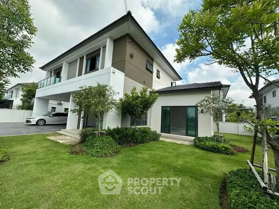 Modern two-story house with lush green lawn and sleek car in driveway, showcasing contemporary architecture.