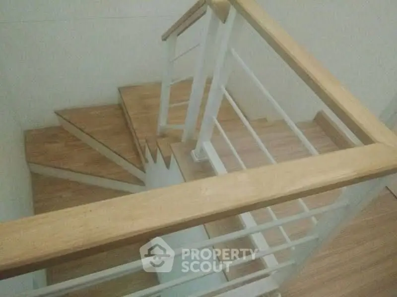 Modern wooden staircase with sleek railing in a contemporary home interior.