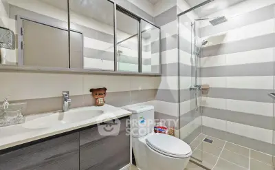 Modern bathroom with sleek fixtures and striped tile design, featuring a spacious shower and stylish vanity.
