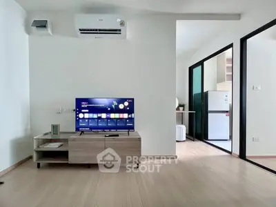 Modern living room with sleek TV setup and view into a contemporary kitchen.