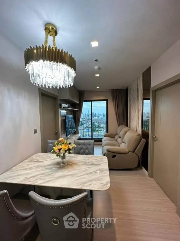 Luxurious living room with elegant chandelier and stunning city view from balcony.