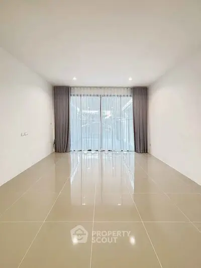 Spacious empty room with large windows and elegant curtains, perfect for customization.