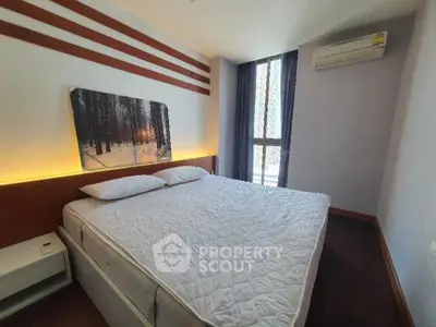 Modern bedroom with large bed, stylish decor, and natural light from a tall window.