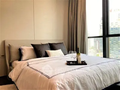 Luxurious bedroom with city view, elegant bedding, and wine setup, perfect for relaxation and comfort.