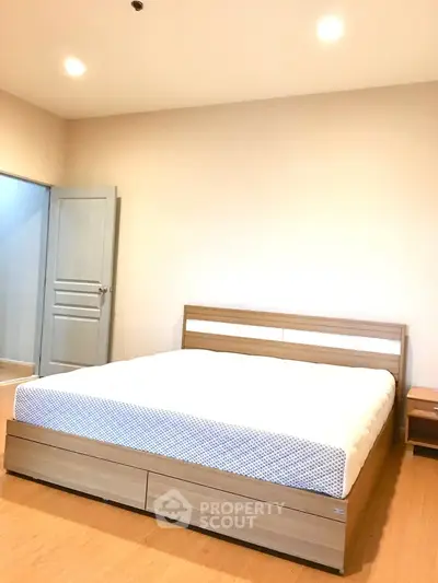 Spacious bedroom with modern wooden bed frame and soft lighting, perfect for relaxation.