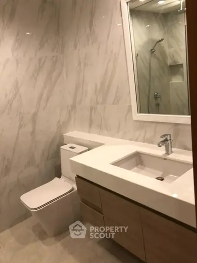 Modern bathroom with sleek fixtures and marble walls in a contemporary home.