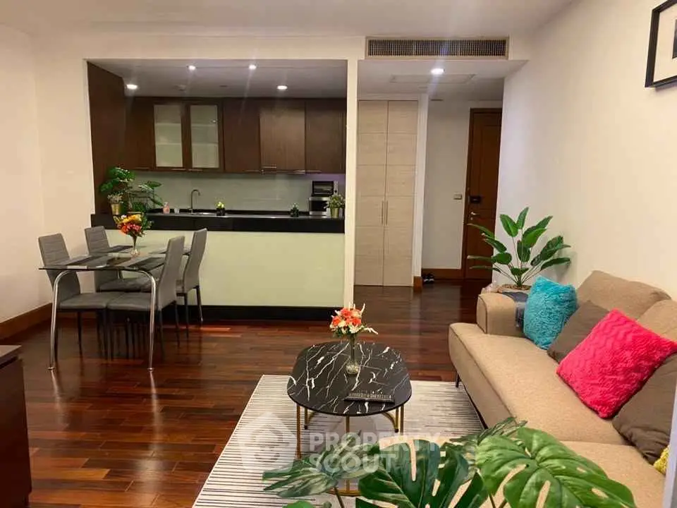 Modern living room with open kitchen, stylish decor, and hardwood floors.