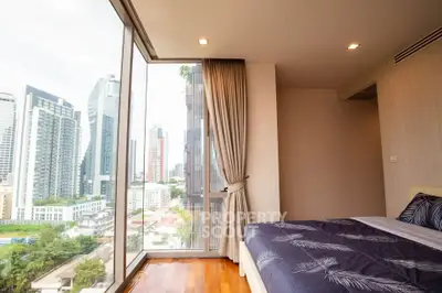 Luxurious bedroom with floor-to-ceiling windows offering stunning city views in a modern high-rise apartment.