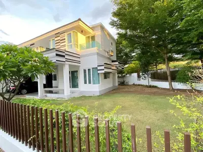 Modern two-story house with lush garden and wooden fence, perfect for family living.