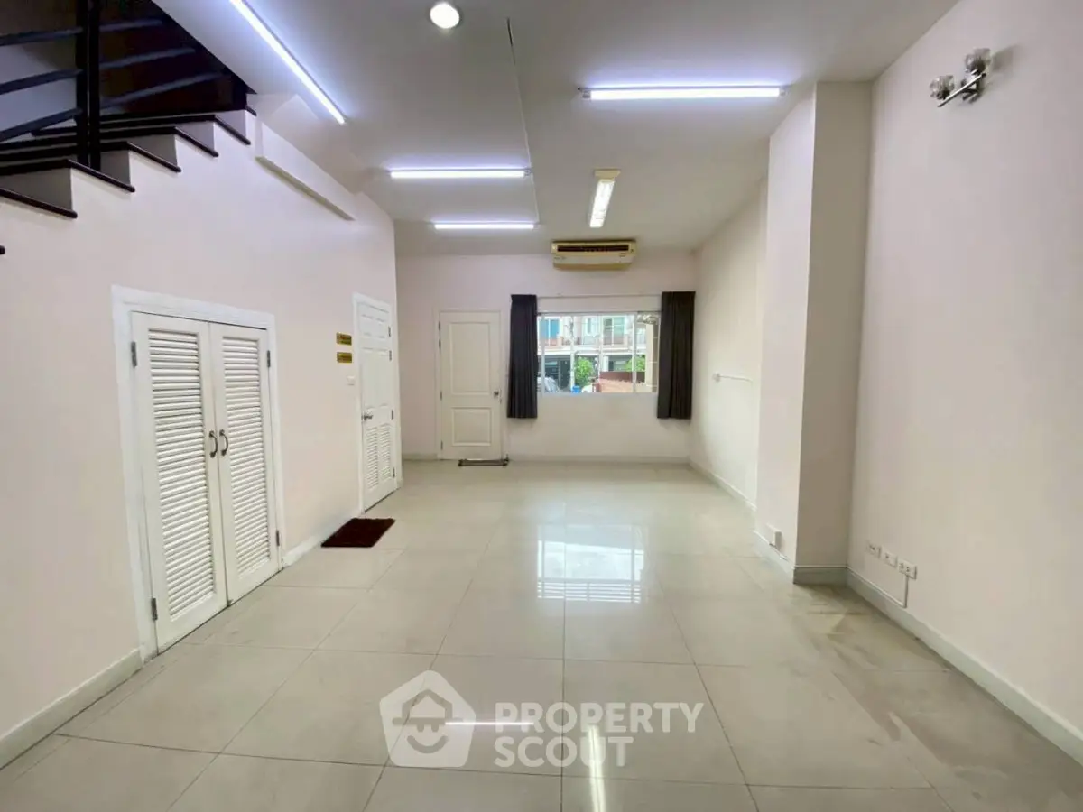 Spacious interior with modern lighting and large window, ideal for versatile living space.