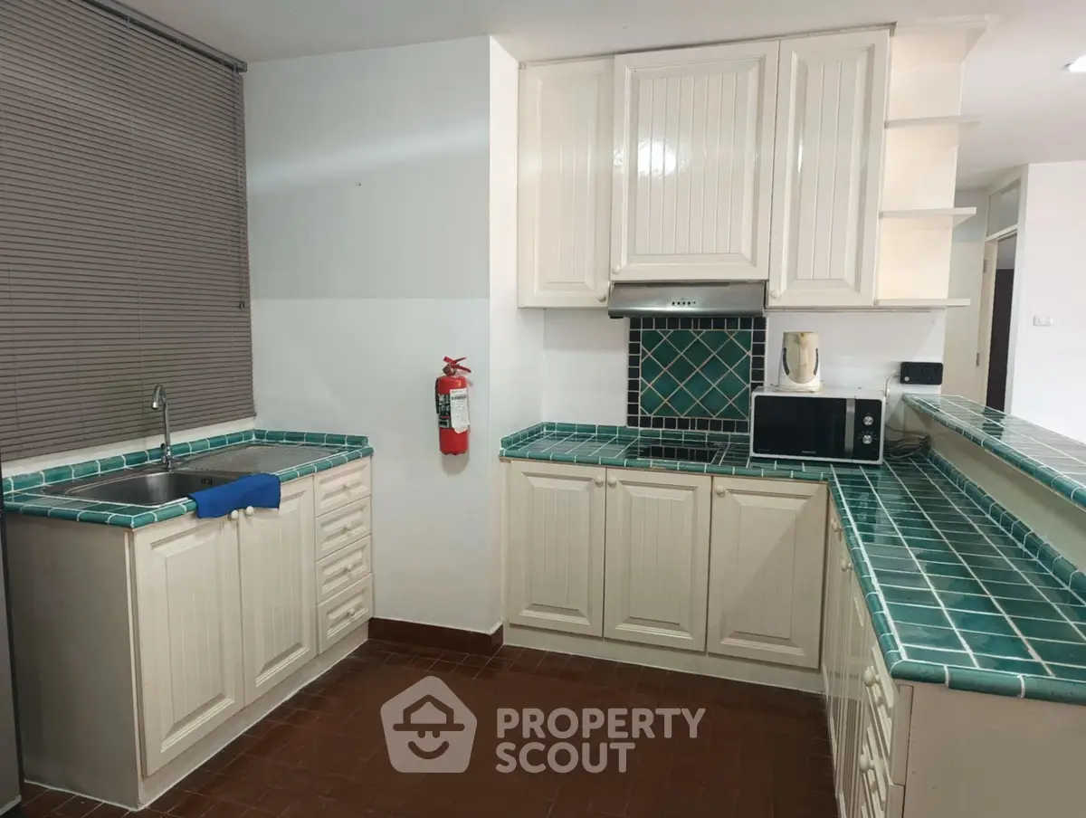 Charming kitchen with teal tile countertops and modern appliances